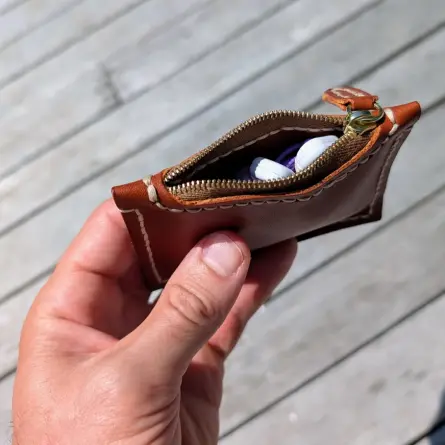 a small zip pouch for holding earbuds and other small things, held in my left hand over a cedar deck