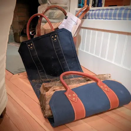 a log carrier---navy blue canvas and chestnut leather straps and rolled handles, with brass rivets, and unfurls next to a hearth